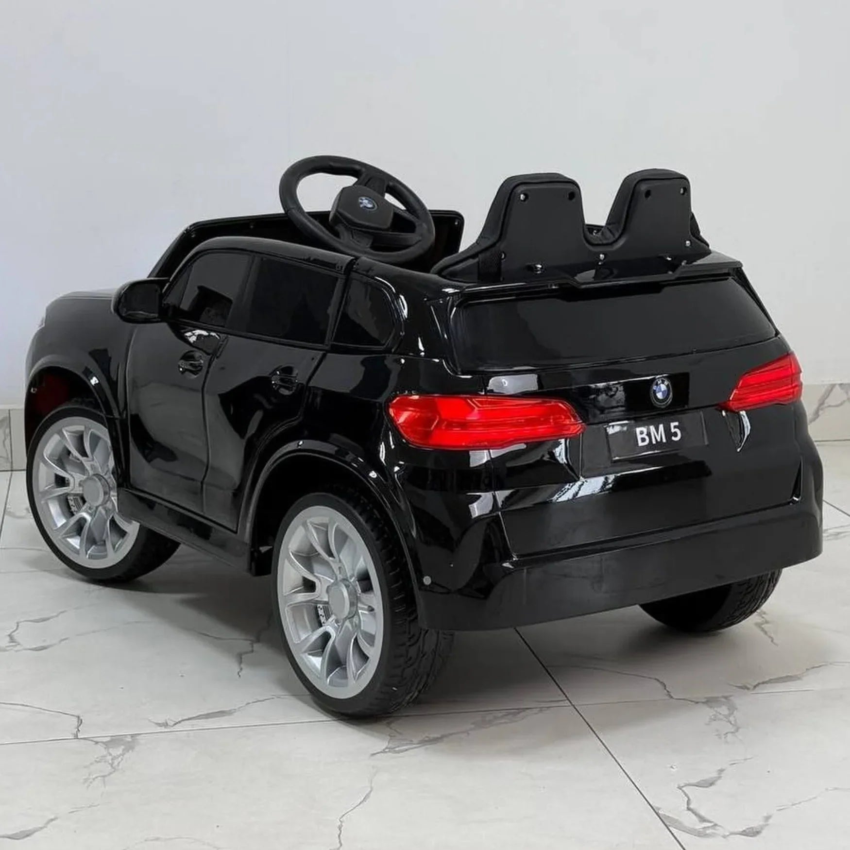 Black toy car with red taillights on a light gray floor