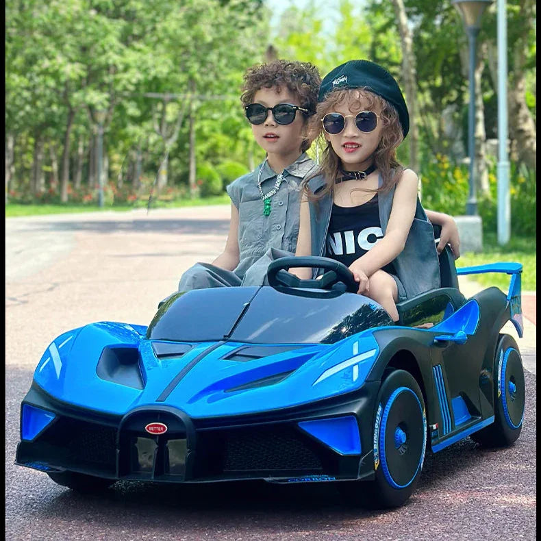 Two children in a blue toy car with sunglasses outdoors.