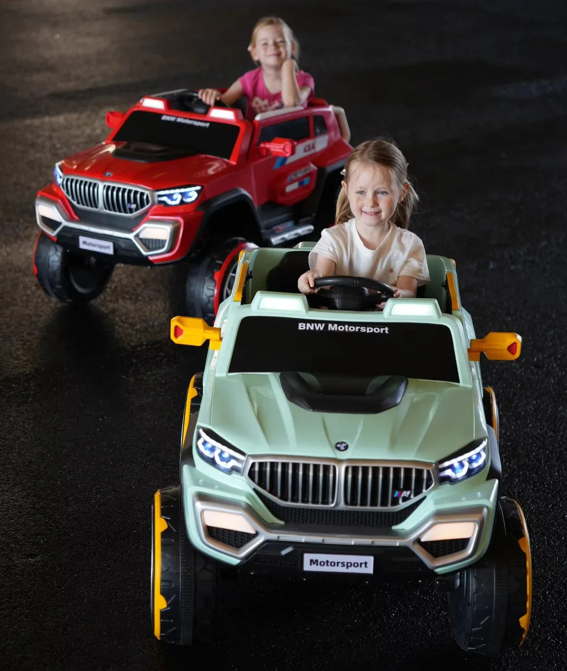 Two children playing with toy cars on a dark surface