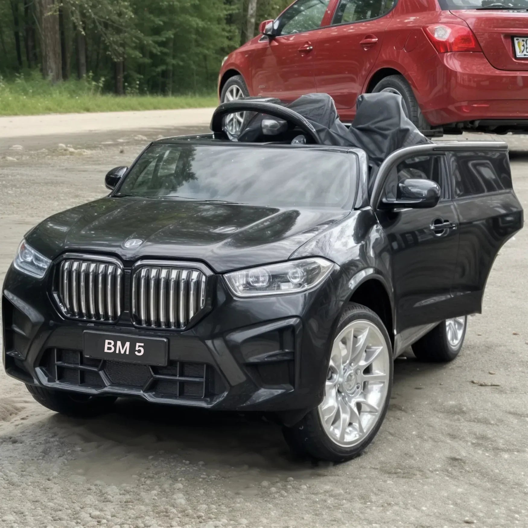 Black toy car resembling a BMW with 'BM 5' on the front, parked outdoors.