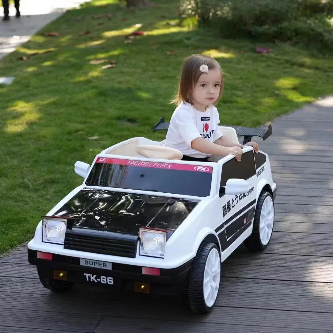 Child in a toy car on a wooden deck with grass and trees in the background