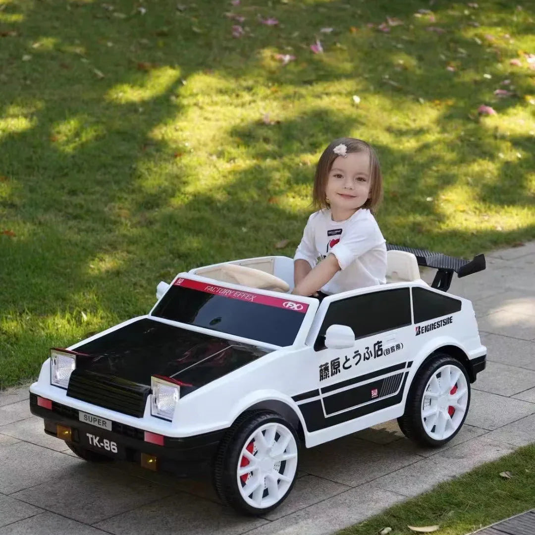 Child sitting in a toy car on a sidewalk with grass in the background