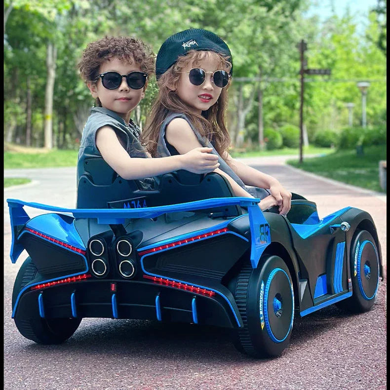Two children in a blue toy car with sunglasses outdoors.