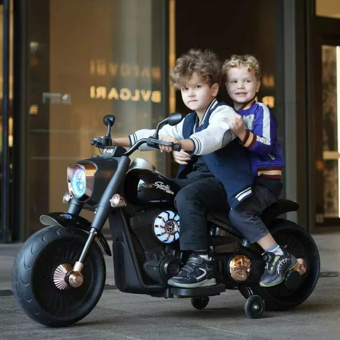 Two children on a toy motorcycle in front of a store entrance.