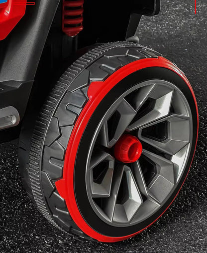 Close-up of a toy car wheel with red rim on a textured surface.