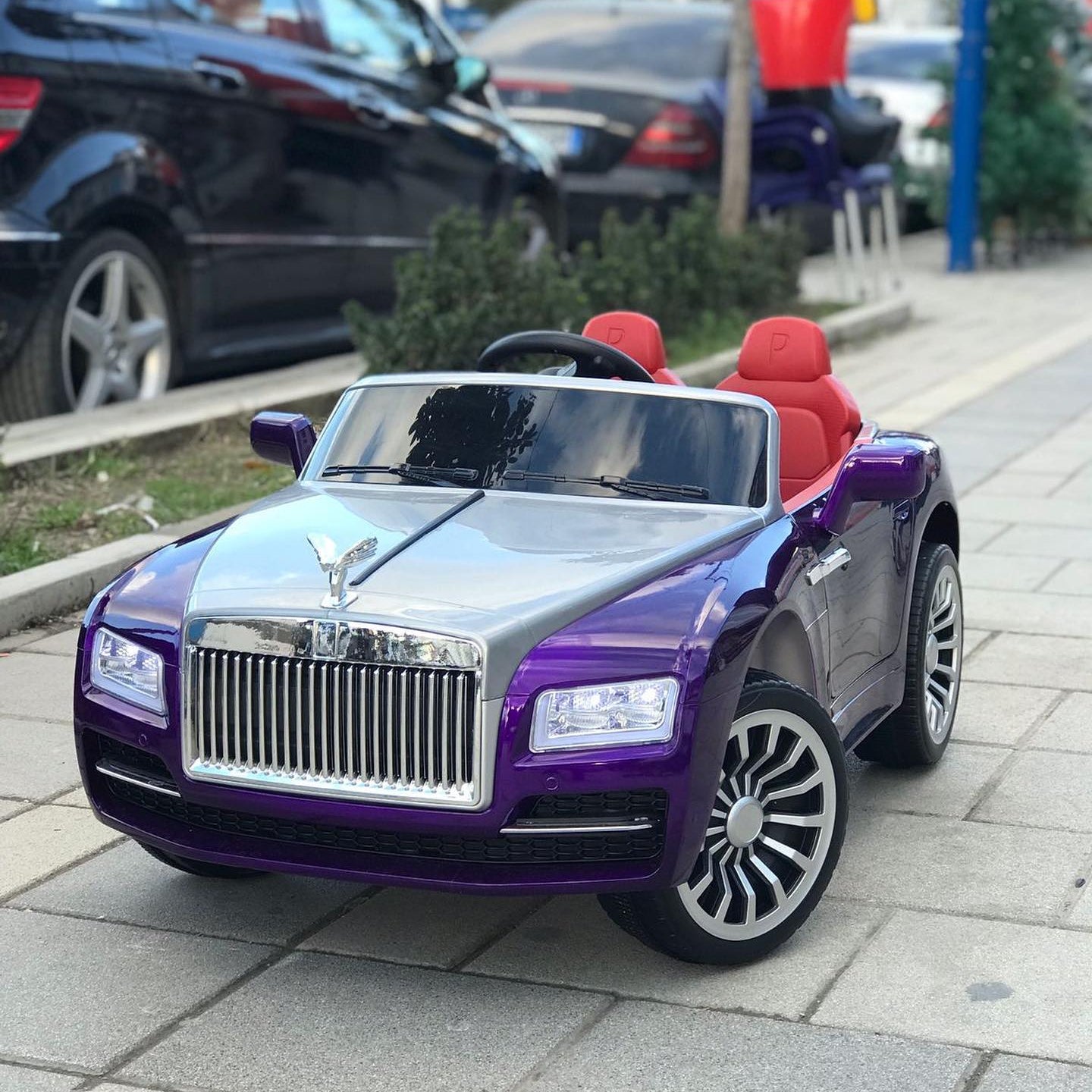 Purple toy car resembling a luxury vehicle on a sidewalk